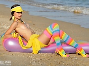 Gorgeous teen beauty in bright stockings showing hot body on the air mattress on the beach.