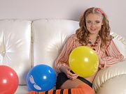 Beautiful shapely teen honey with colorful balloons taking off her clothes on the sofa.