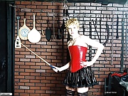 Blonde in vinyl happily shows off dungeon implements
